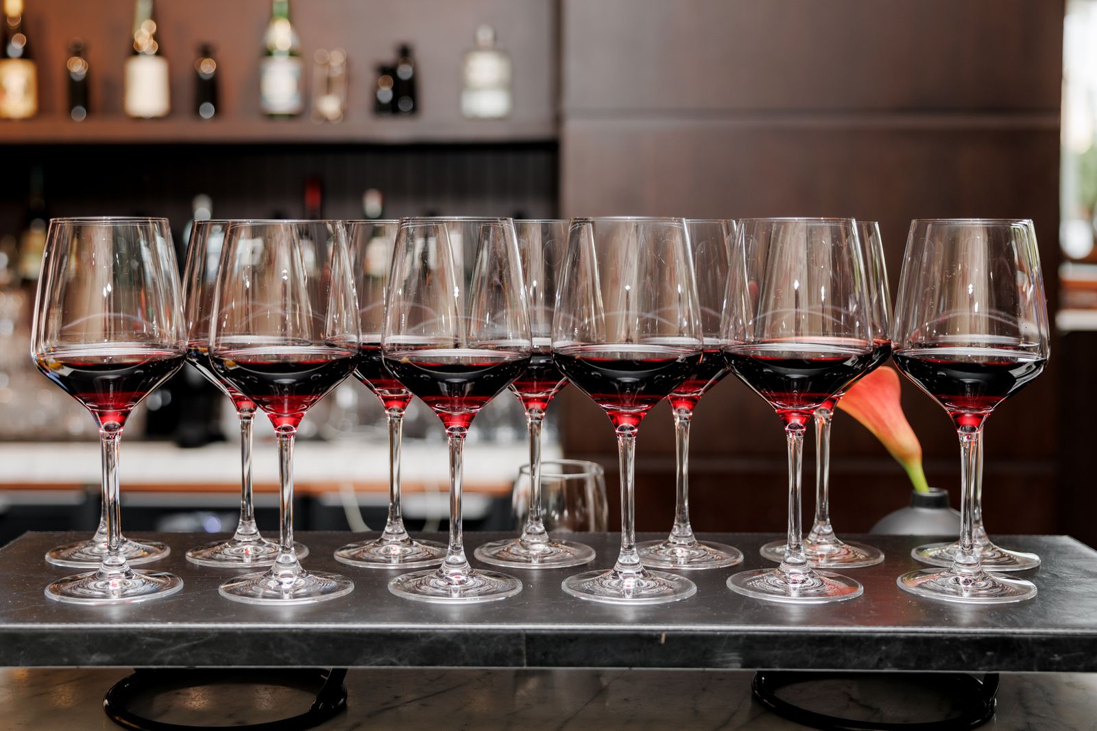 A row of glasses of red wine on a dark marble bar