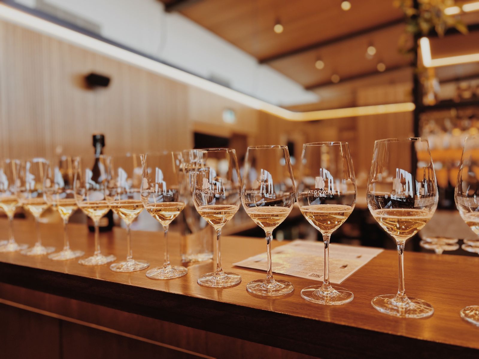 A row of wine glasses on a wooden bar, ready for a tasting